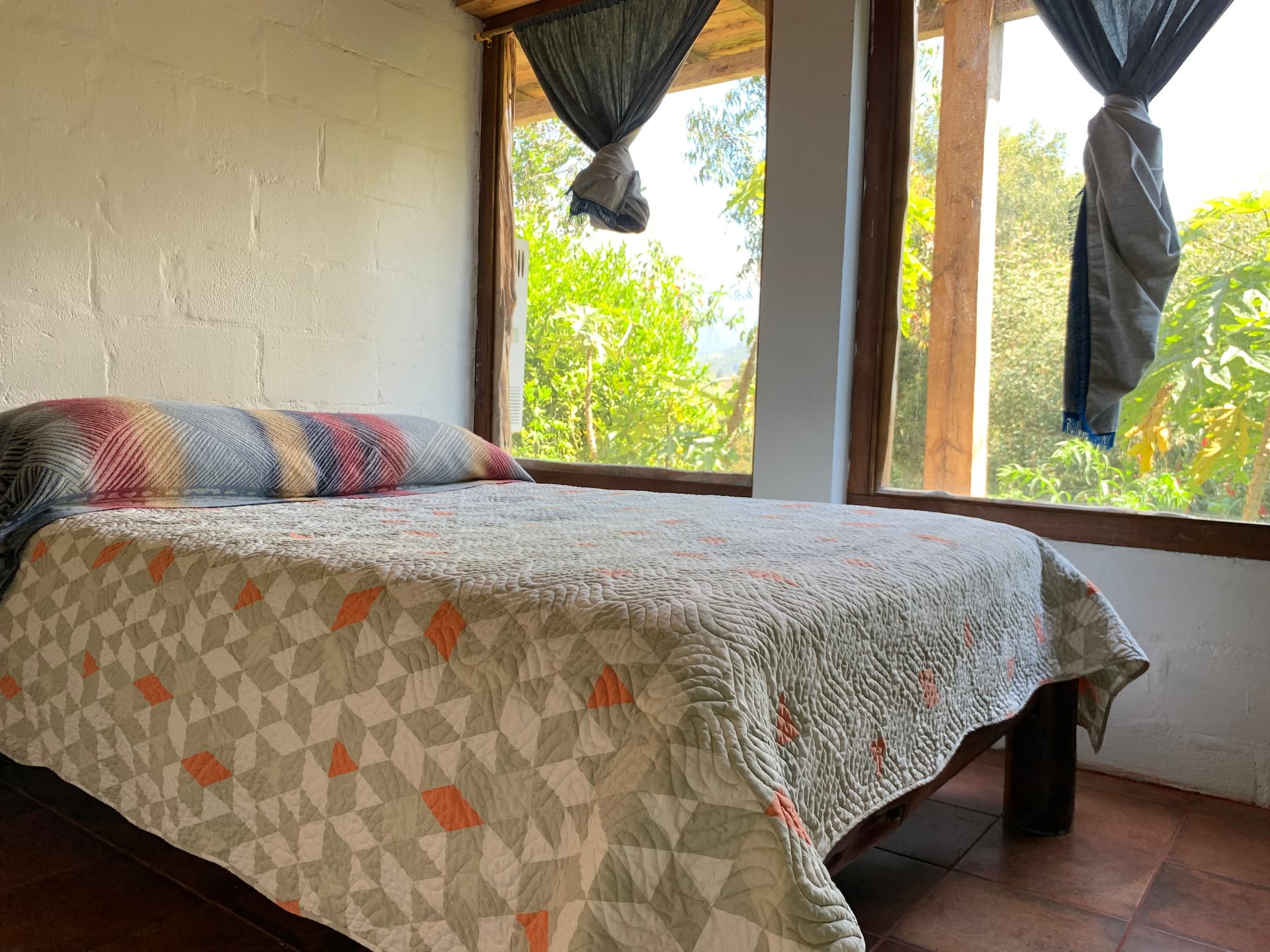 Dormitorio con cama queen y grandes ventanales